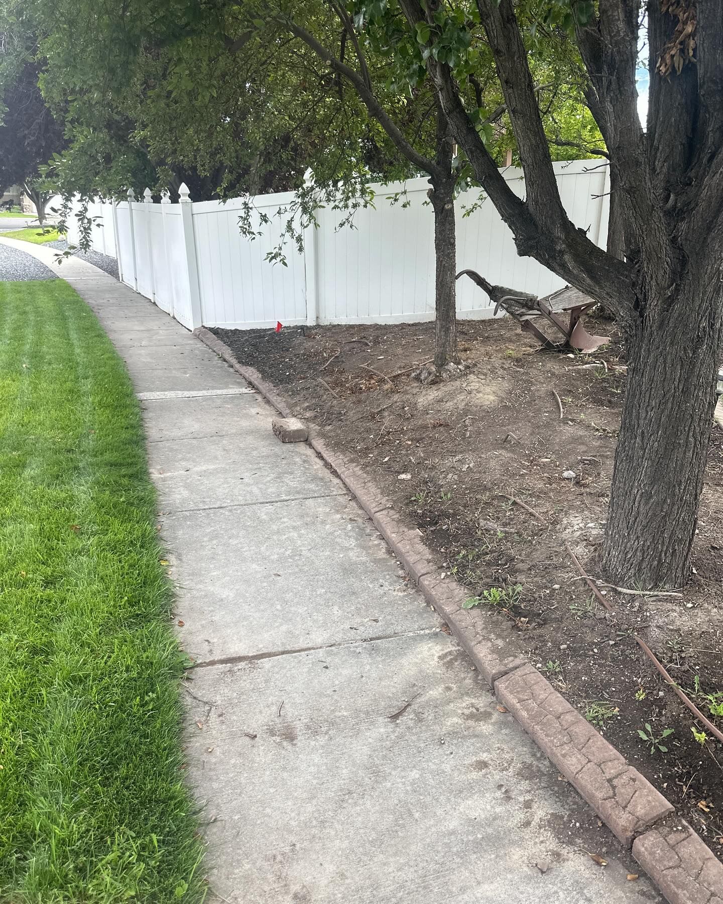 A sidewalk with a white fence along the side of it