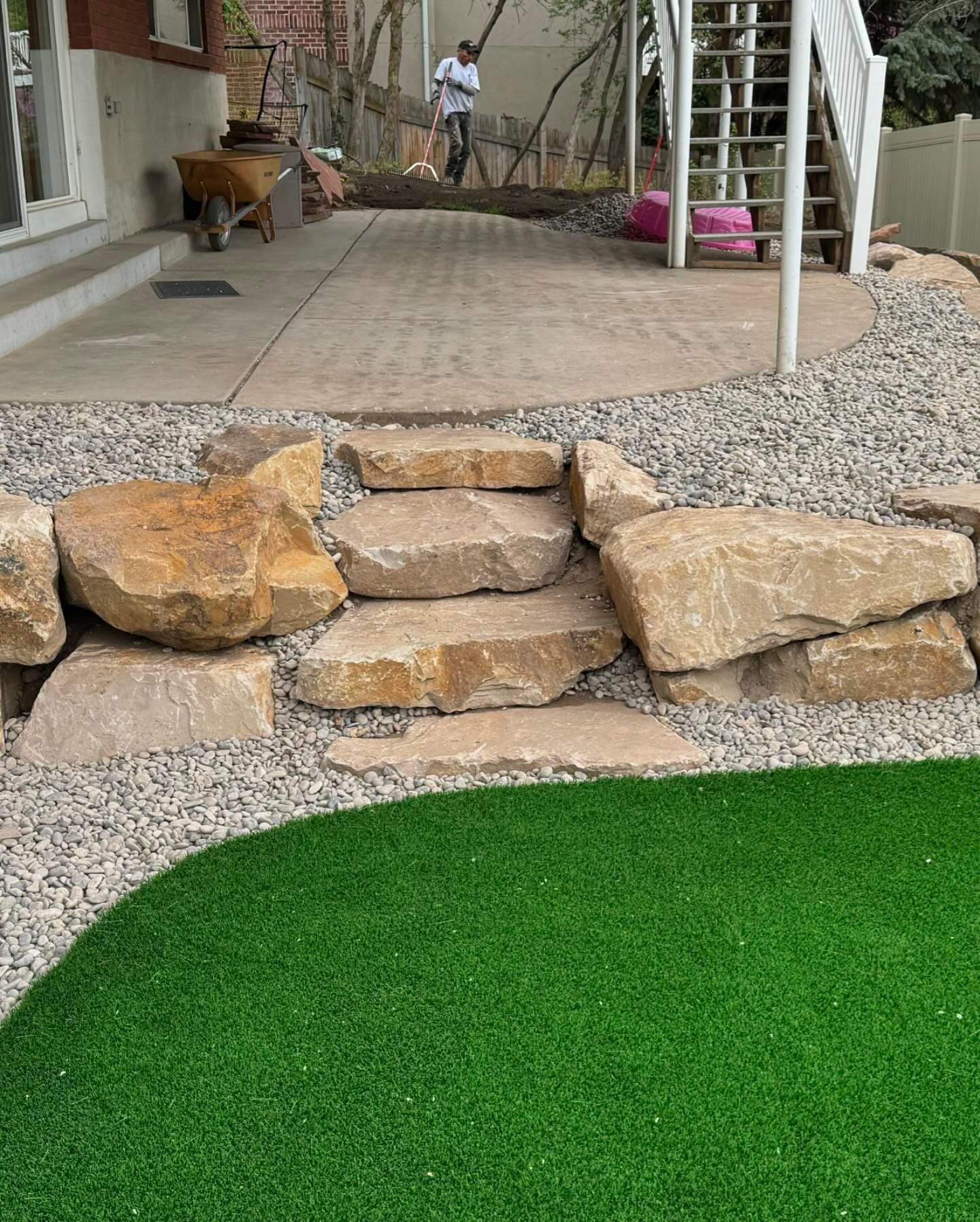 A man is standing on a patio next to a rock wall and stairs.