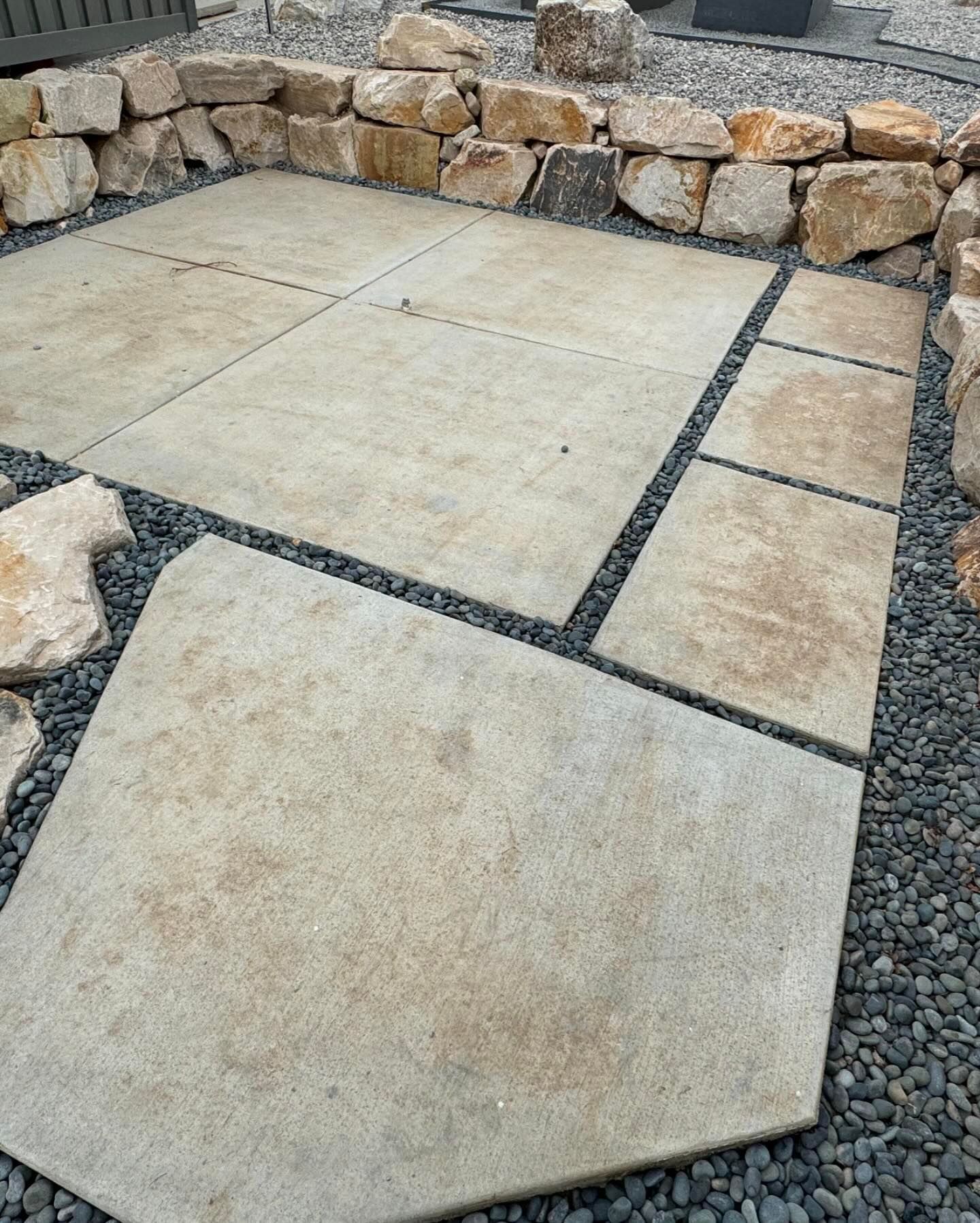 A patio with tiles and rocks in the background.