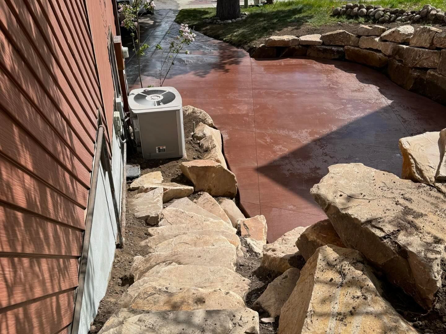 A house with a concrete patio and rocks in front of it.