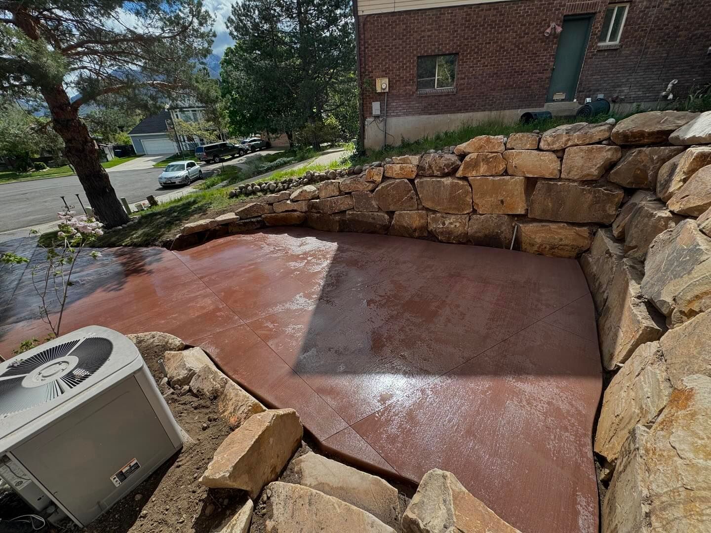 A white air conditioner is sitting on a concrete patio next to a stone wall.