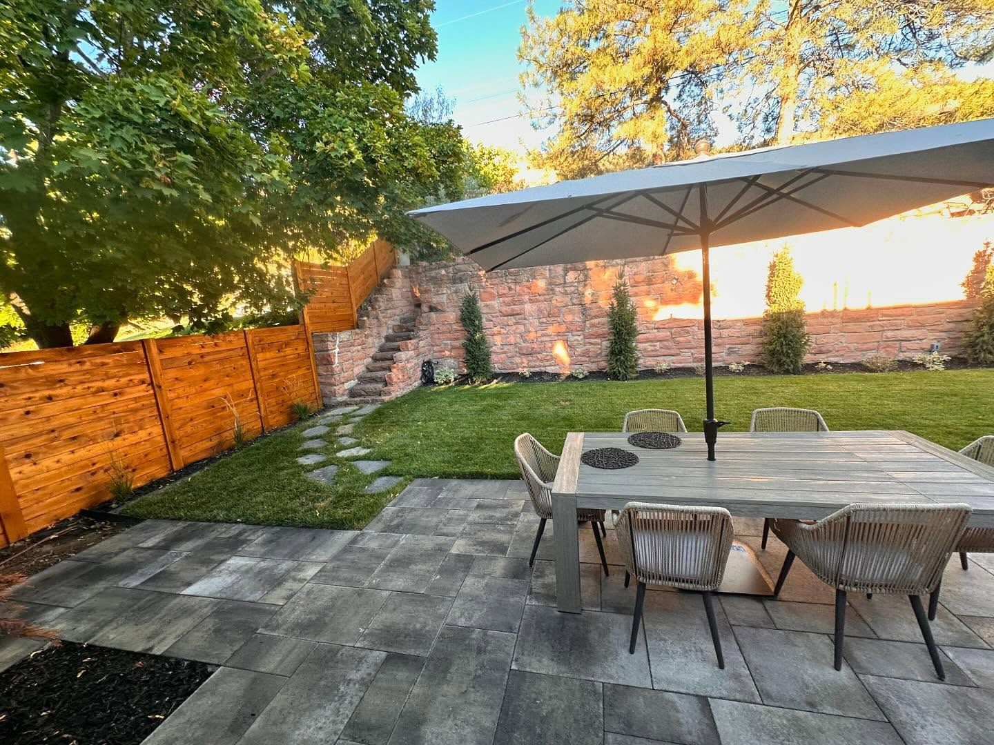 A patio with a table and chairs and an umbrella in the backyard.