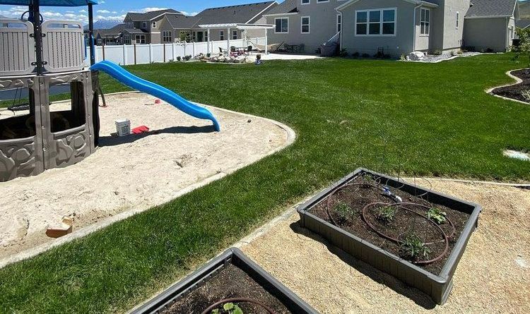 A backyard with a slide , sandbox , and planters.
