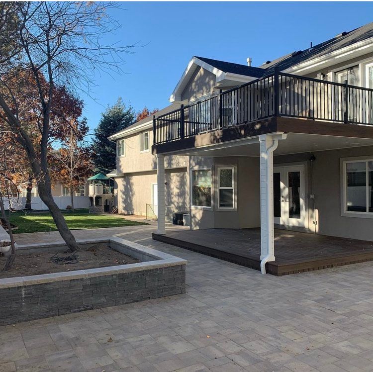 A patio with a tree in the middle of it in front of a house.