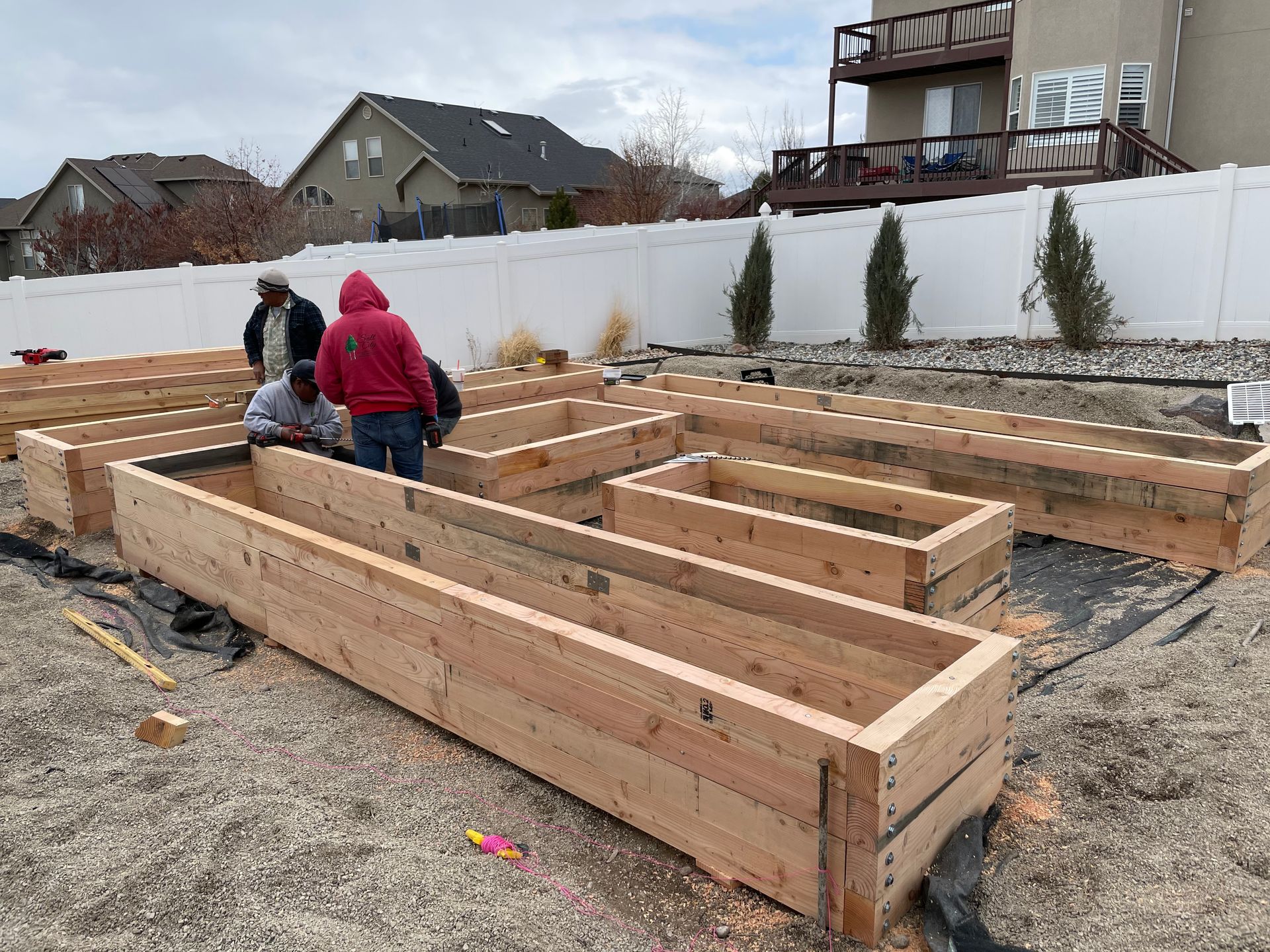 A group of people are working on a wooden structure in a yard.