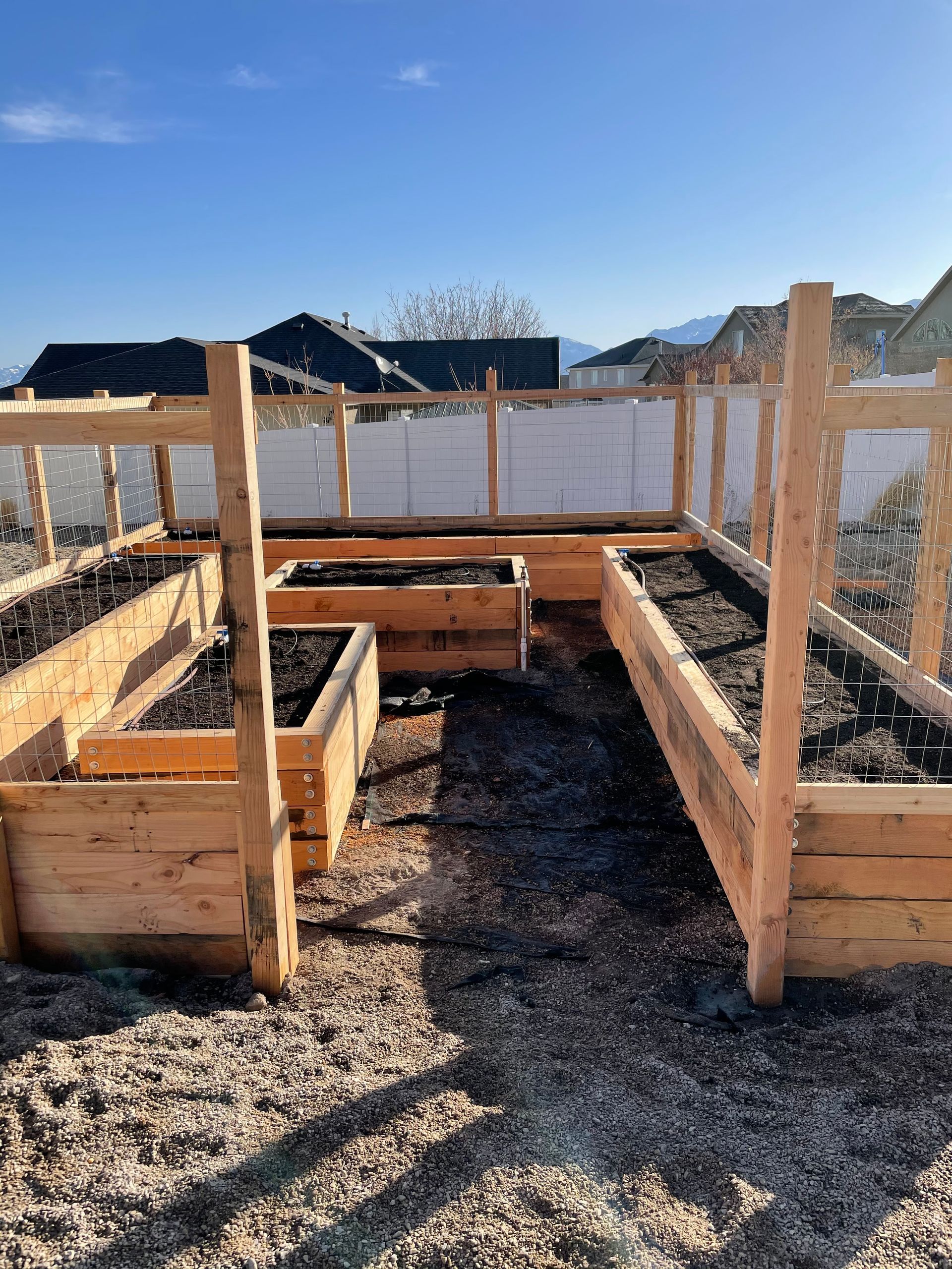 A wooden greenhouse is being built in a backyard.
