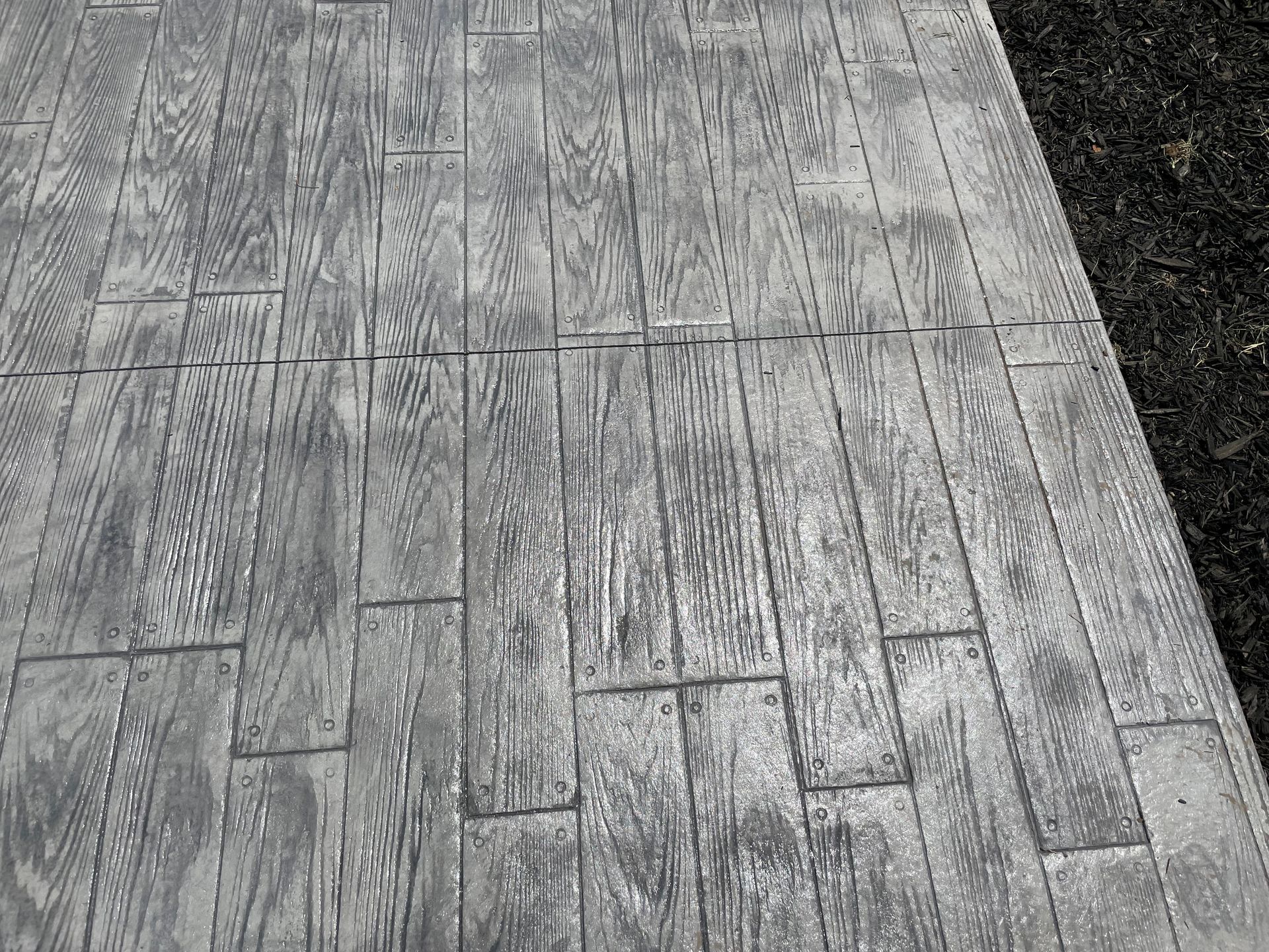 A black and white photo of a concrete walkway that looks like wood.