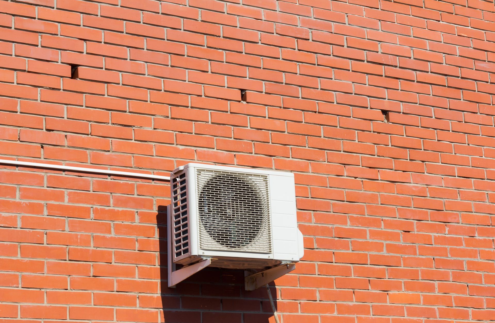 an air conditioner is mounted on the side of a brick building .