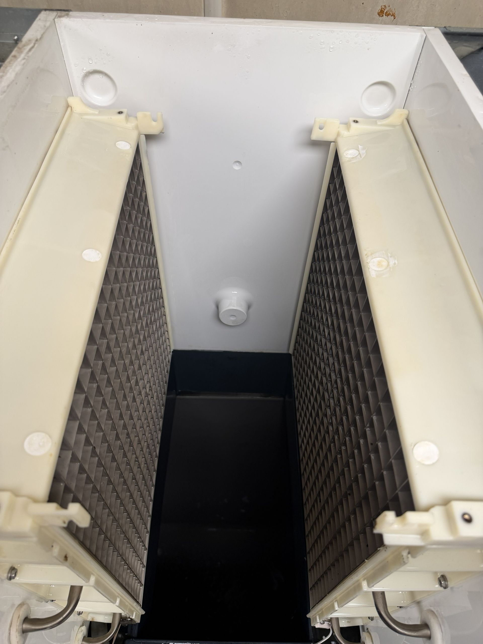 Open electrical cabinet with two cream-colored panels and dark filter sections inside.