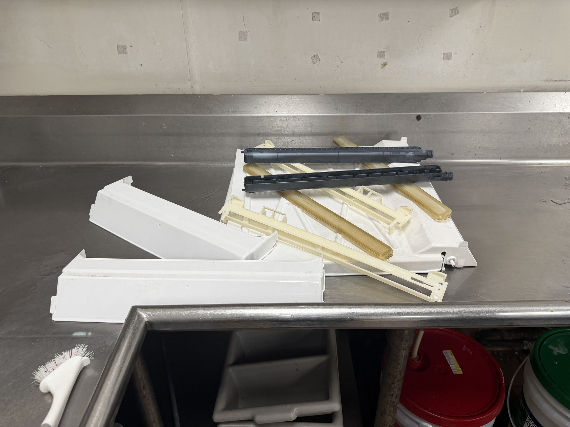 Metal sink with stacked white takeout boxes and black utensils on a counter