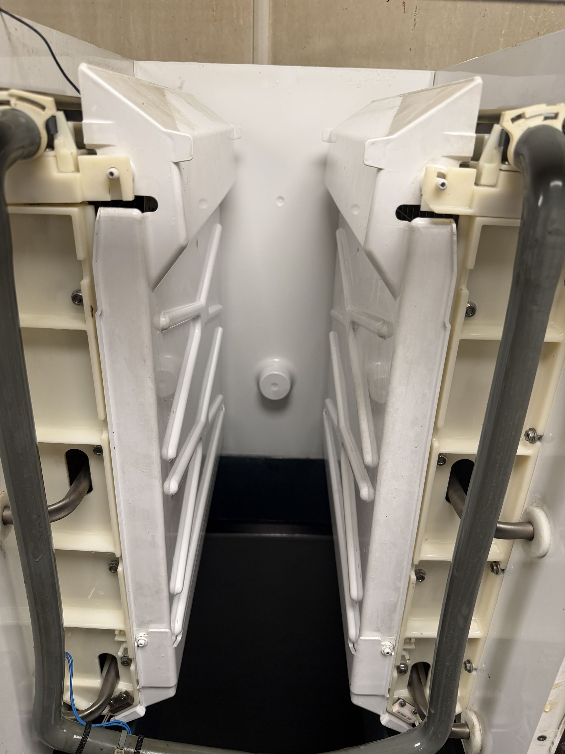 Open white folding lounge seats in a narrow aisle or compartment.