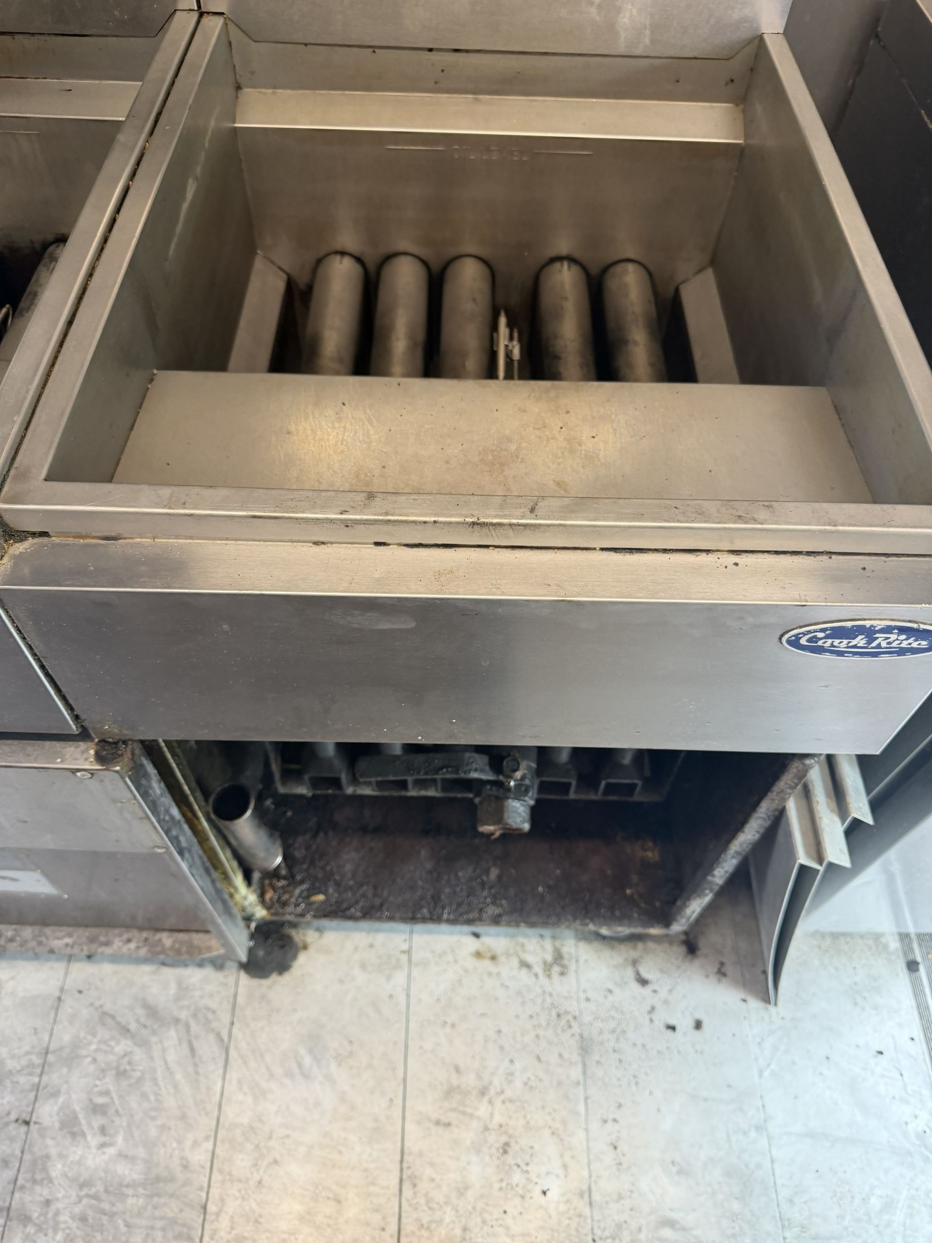Industrial metal sink with coiled pipes inside, viewed from above in a tiled utility area