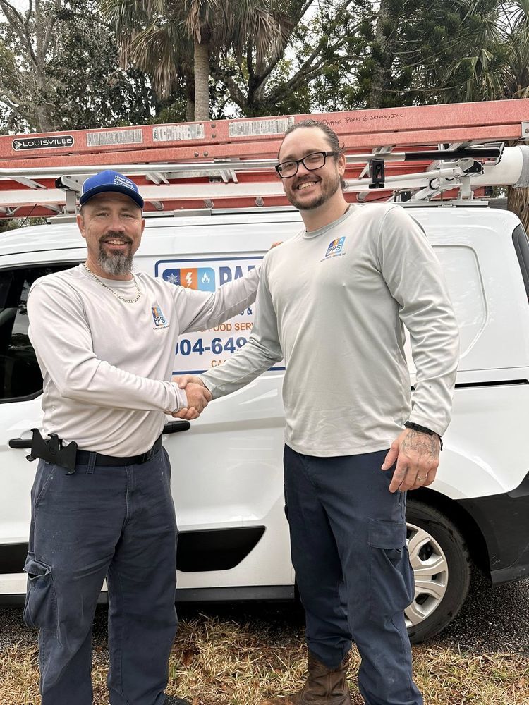 Two men shaking hands beside a white service van with ladders on top.