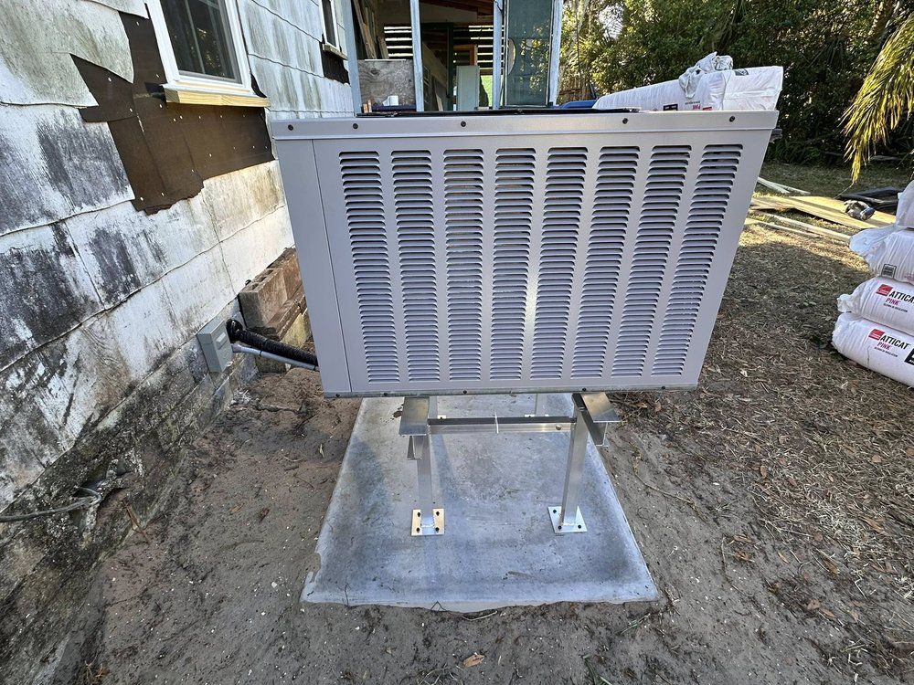 Outdoor HVAC unit on a concrete pad beside a house, with vented metal panels and scattered debris nearby
