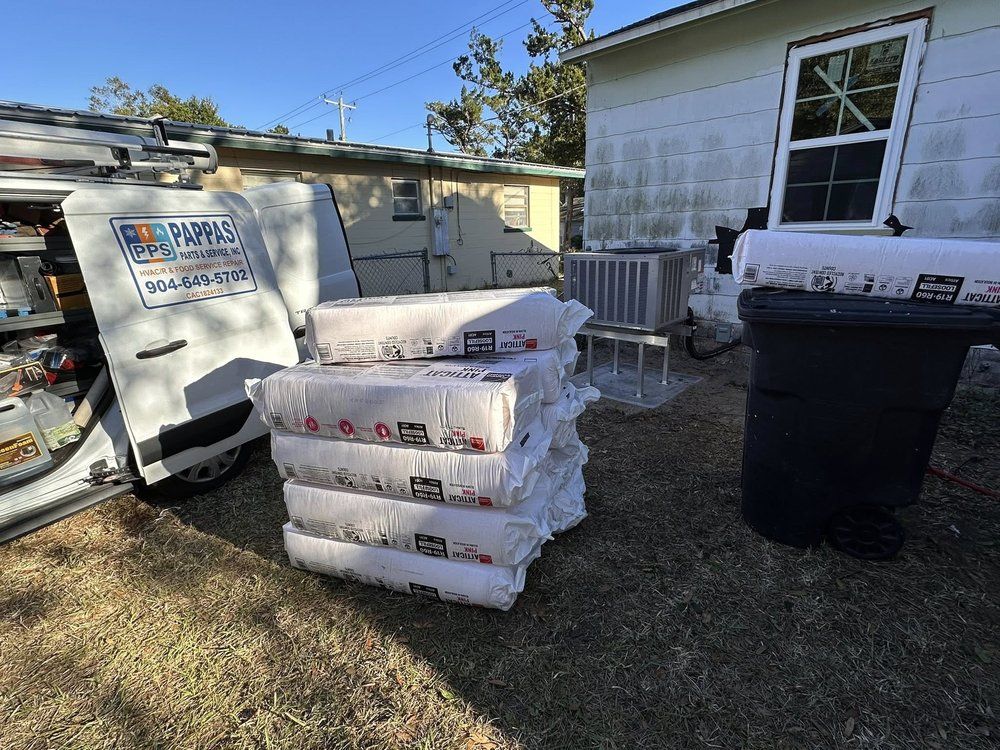 Stacks of bagged materials beside a house, with a service van, trash bin, and garage in the yard.