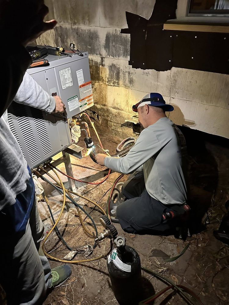 Two workers repairing cables beside a generator in a dark, damp basement.