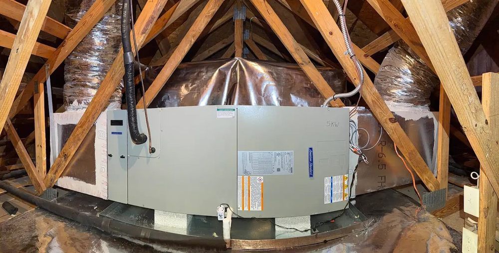 Attic HVAC unit amid exposed wooden rafters and insulation in a cramped attic space