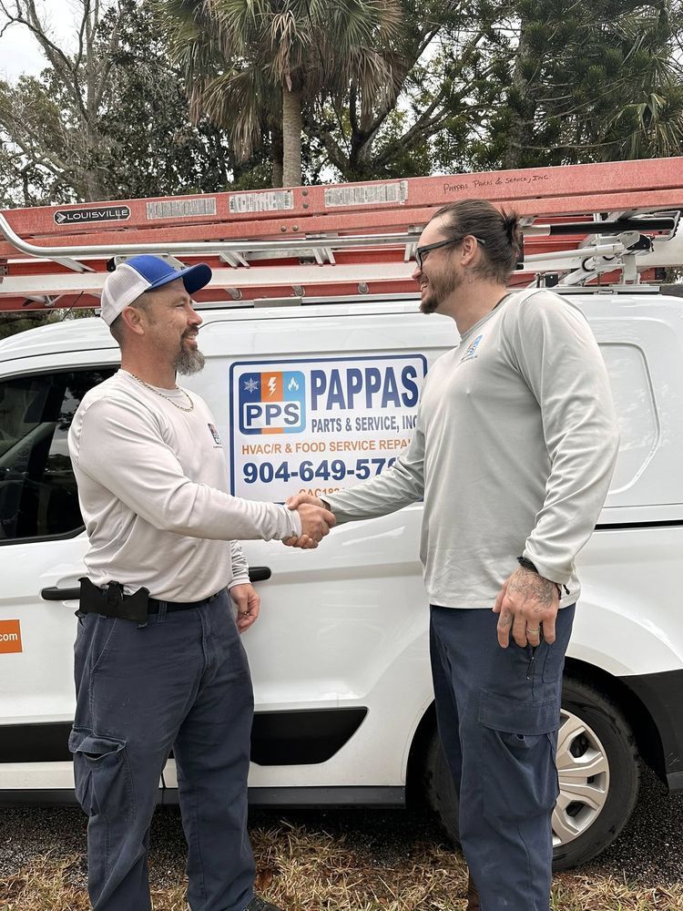 Two men shaking hands beside a white service van with a Pappas sign and ladder on top.
