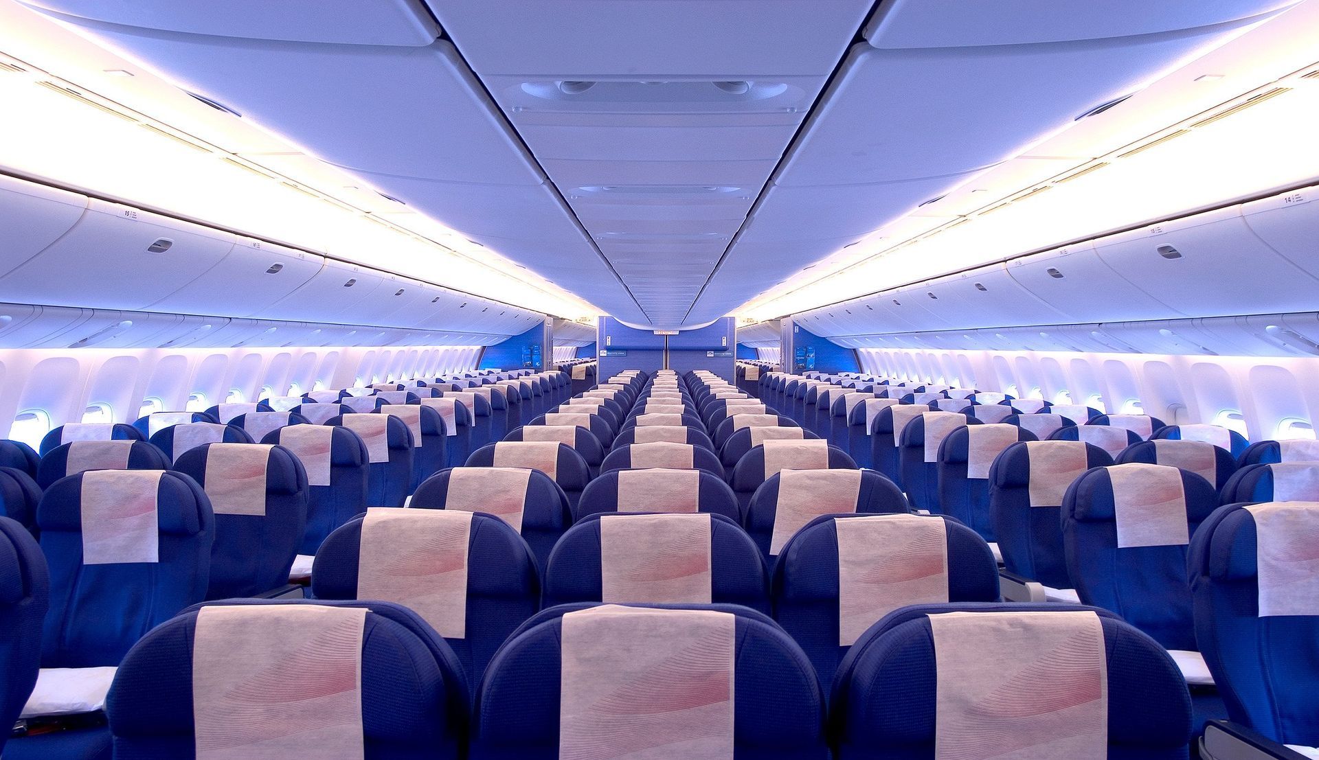 The inside of an airplane with rows of blue seats
