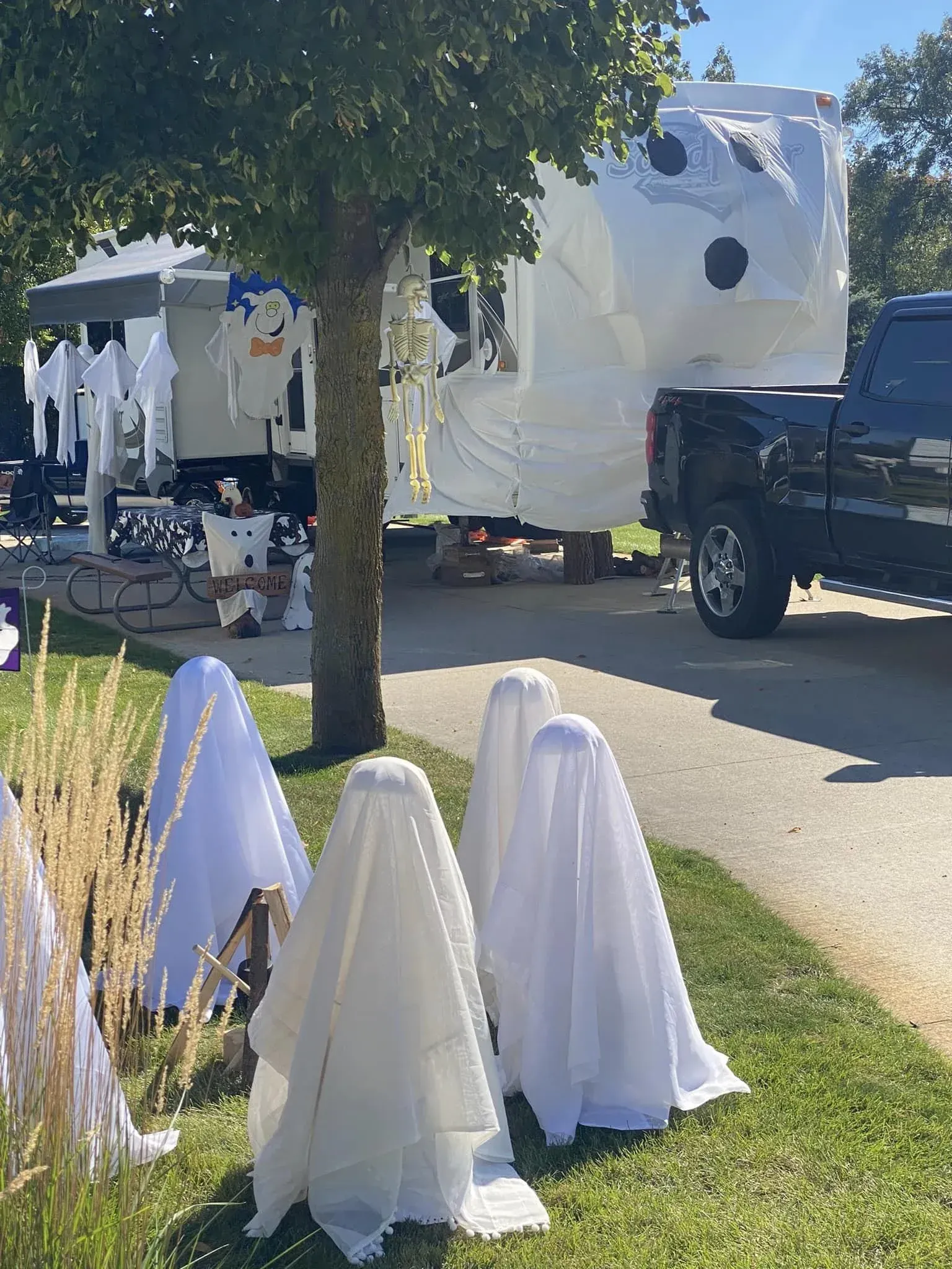 A truck is parked in front of a rv decorated for halloween.