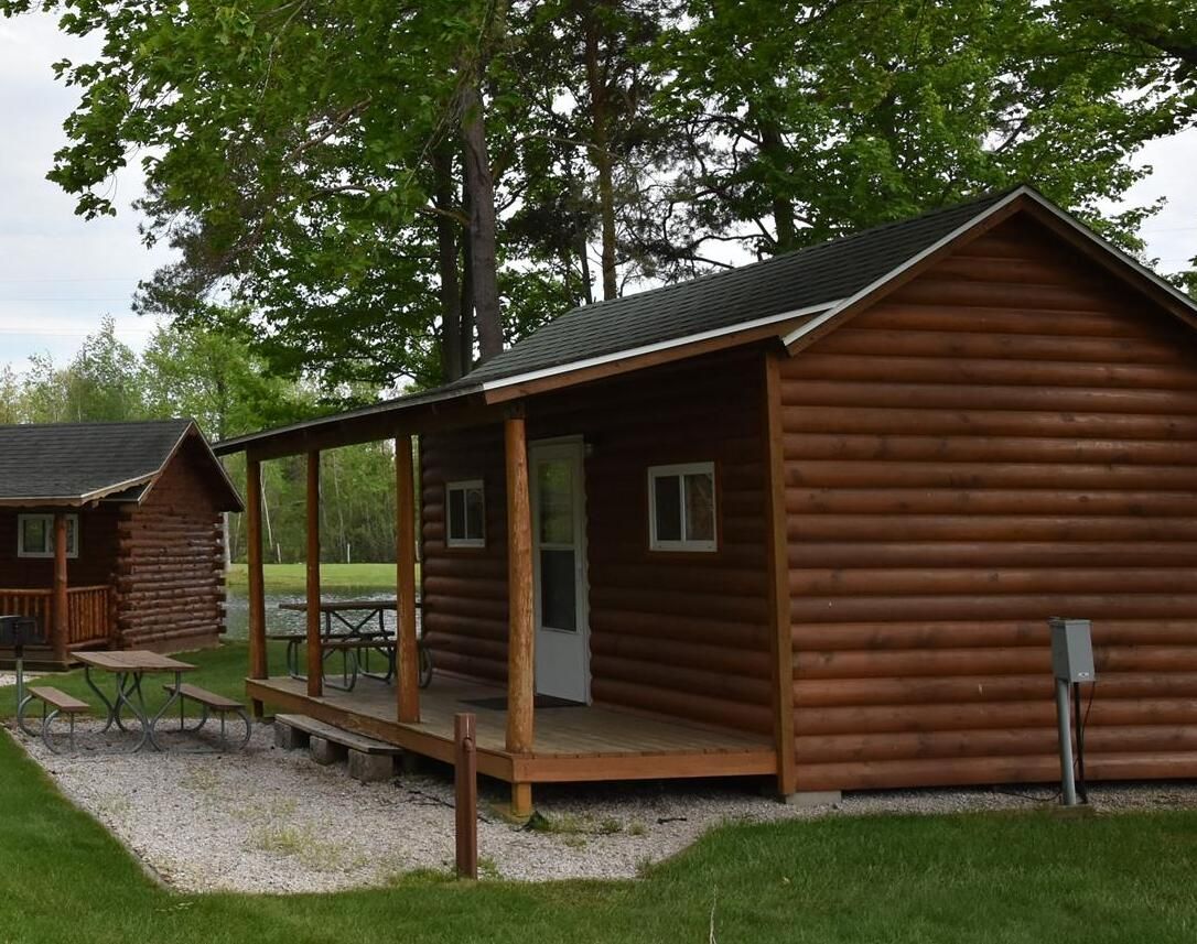 A small log cabin with a porch and a picnic table.