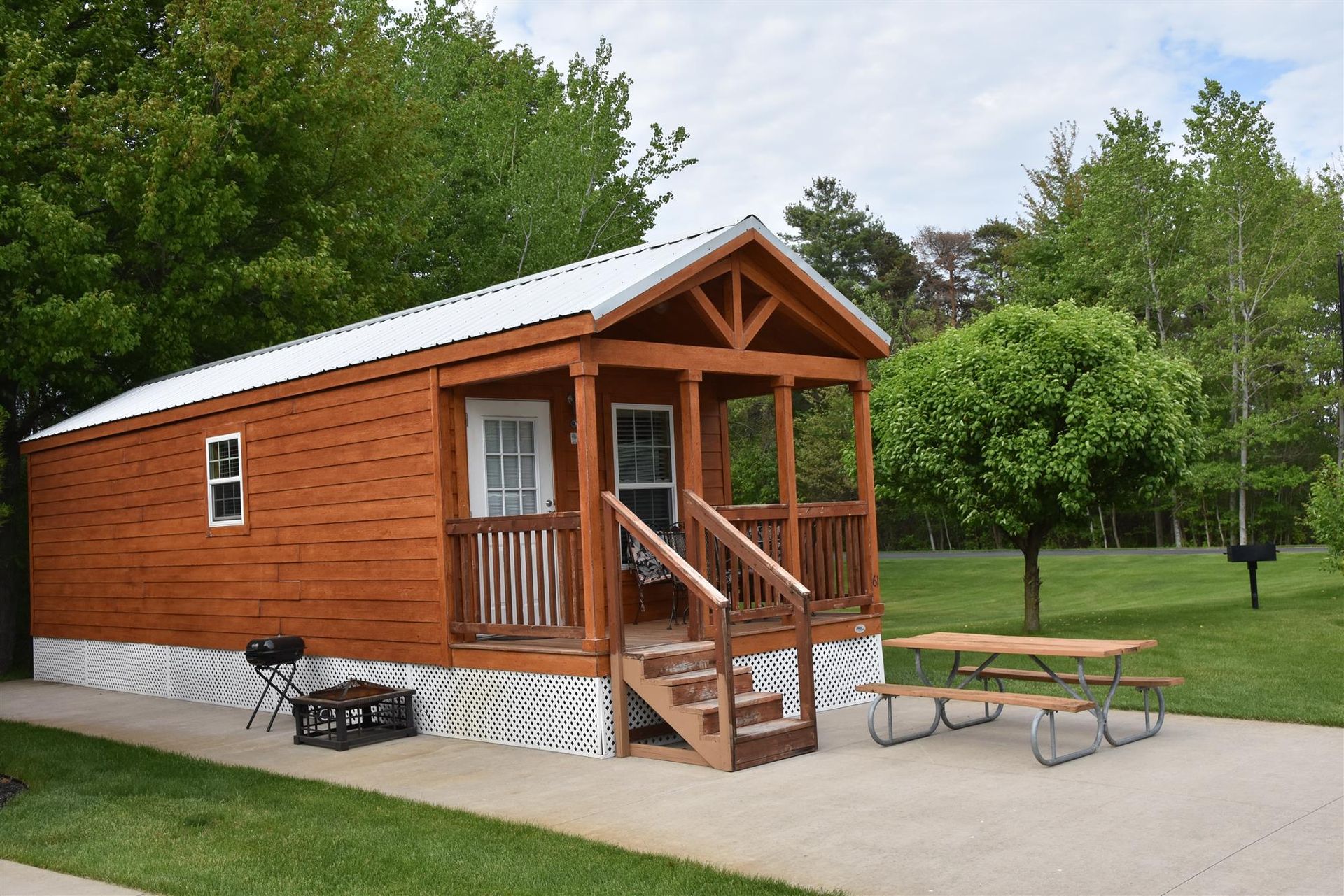 A small wooden cabin with a porch and a picnic table in front of it.
