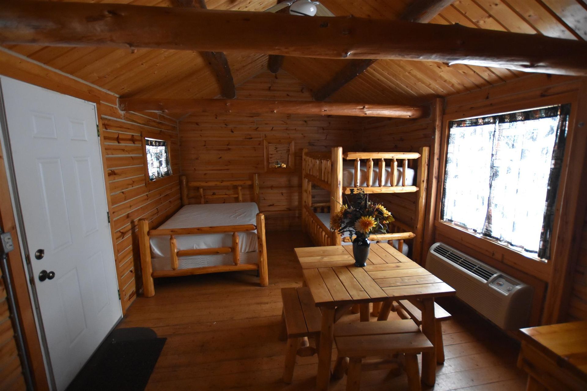 A wooden cabin with bunk beds , a table and benches.