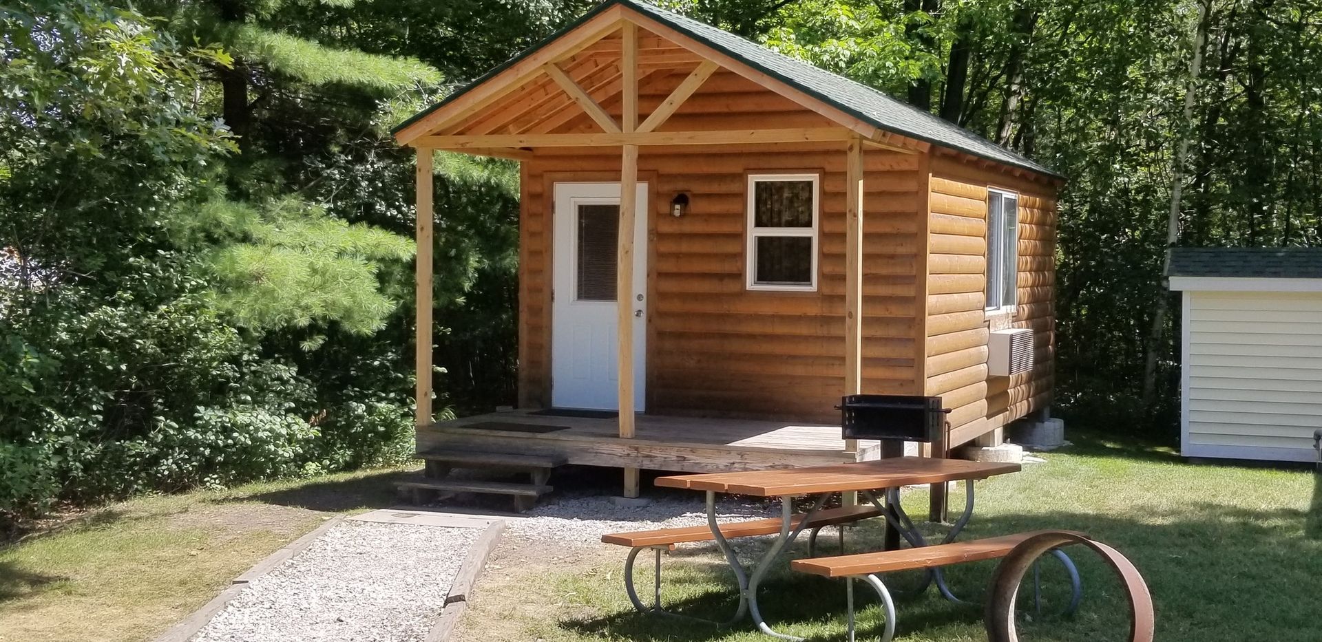 A small log cabin with a picnic table in front of it