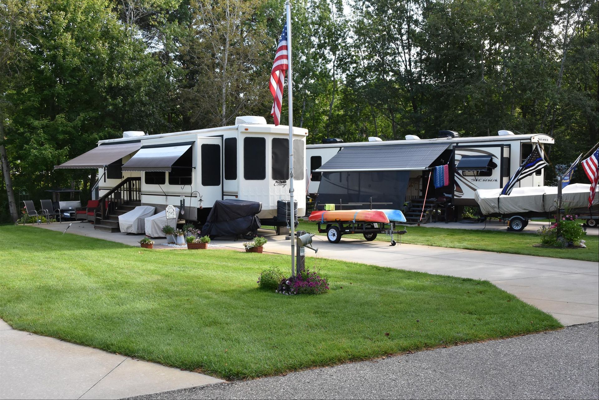 A row of rvs parked in a driveway next to a flag pole.