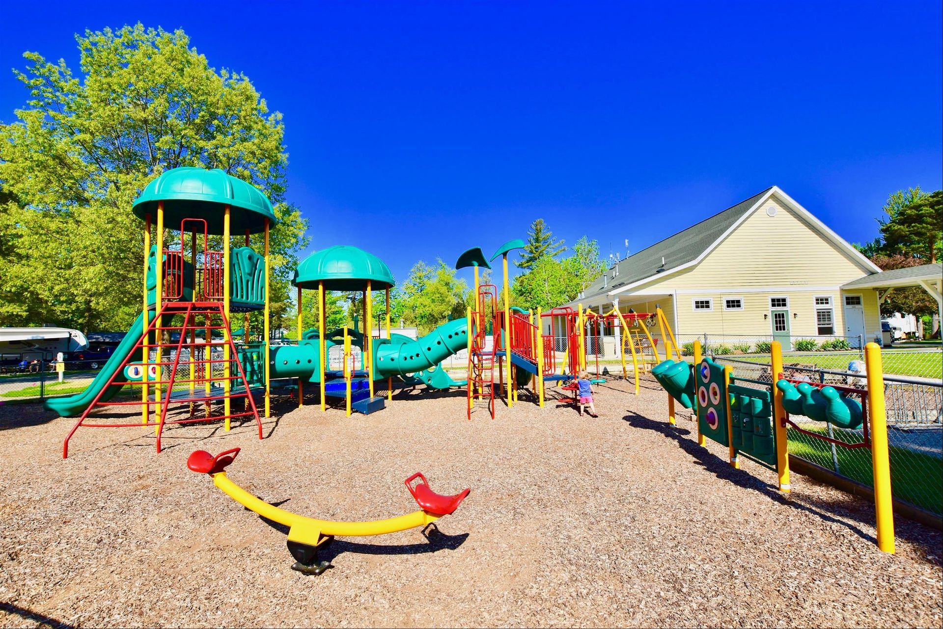 A colorful playground with a house in the background on a sunny day.