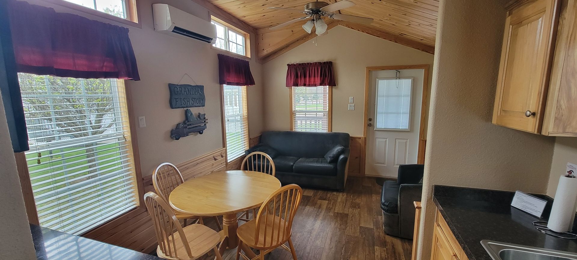 A living room with a couch , table , chairs and a kitchen.