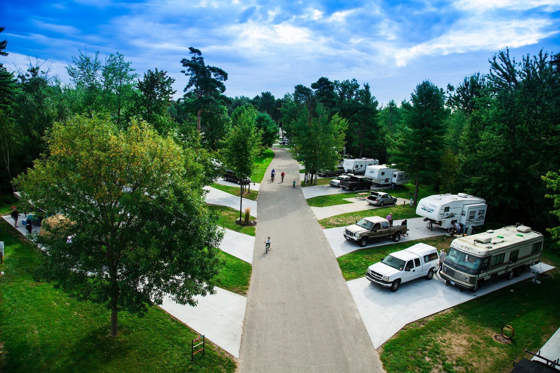 An aerial view of a campground with a lot of rv 's parked on the side of the road.