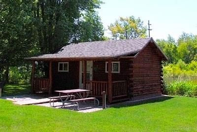 A small log cabin with a picnic table in front of it.