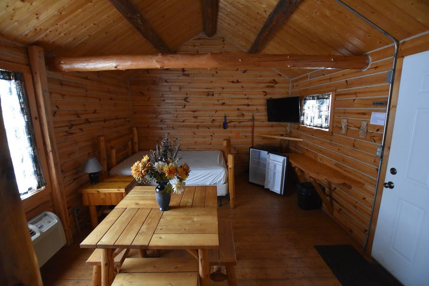 A wooden cabin with a table and a bed