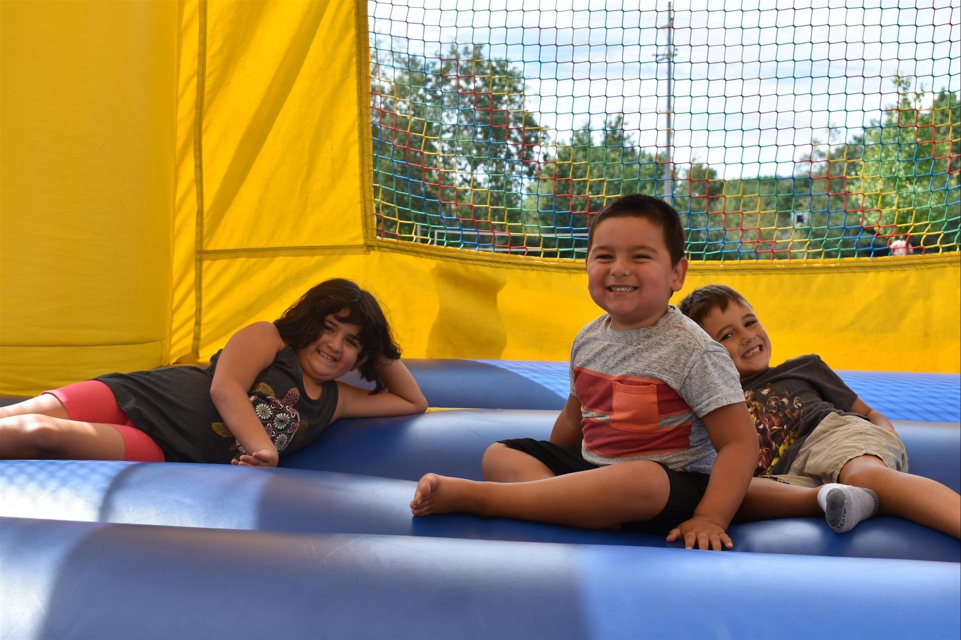 Three children are sitting on a bouncy house.