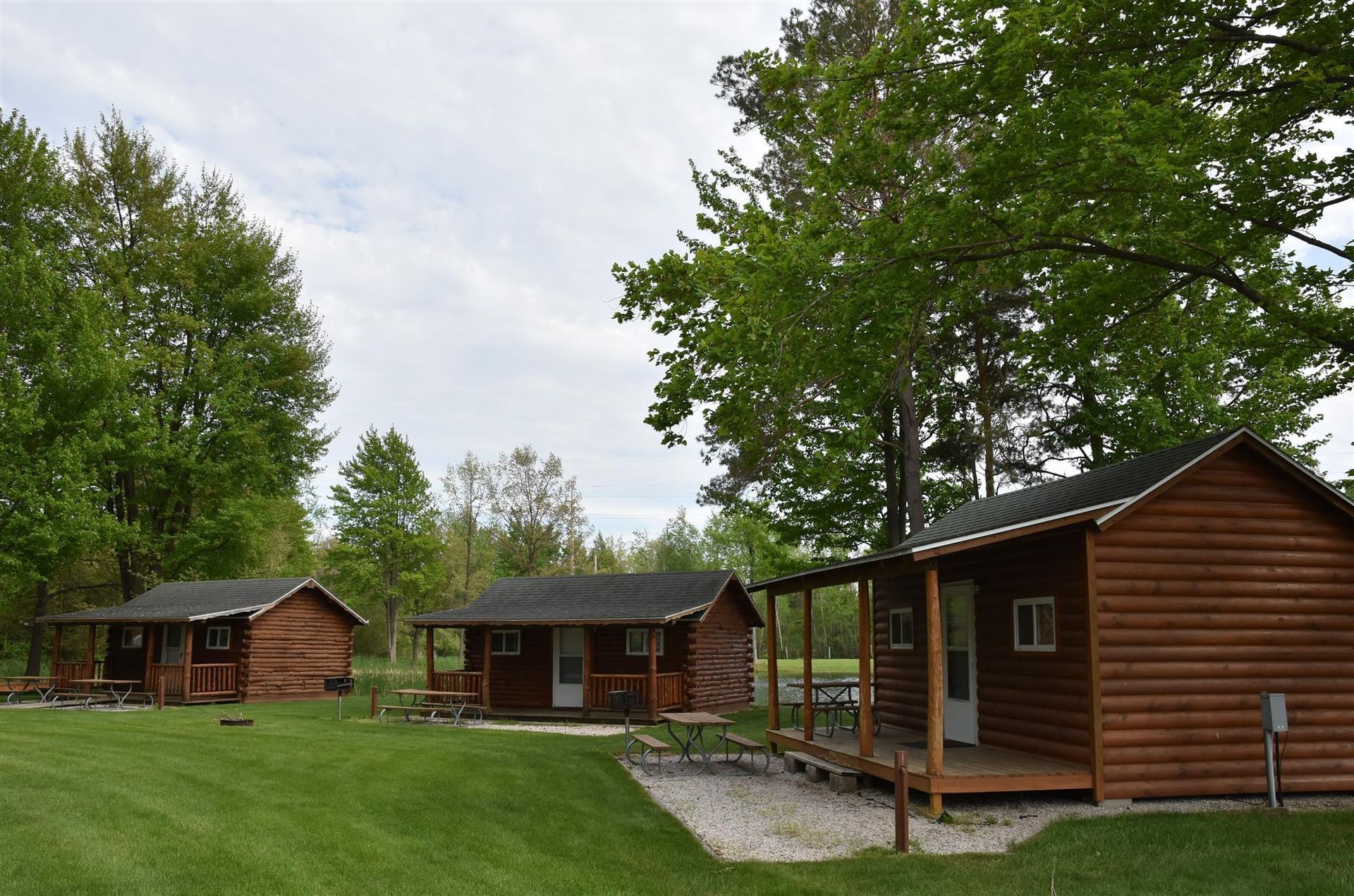 A group of log cabins are sitting on top of a lush green field.