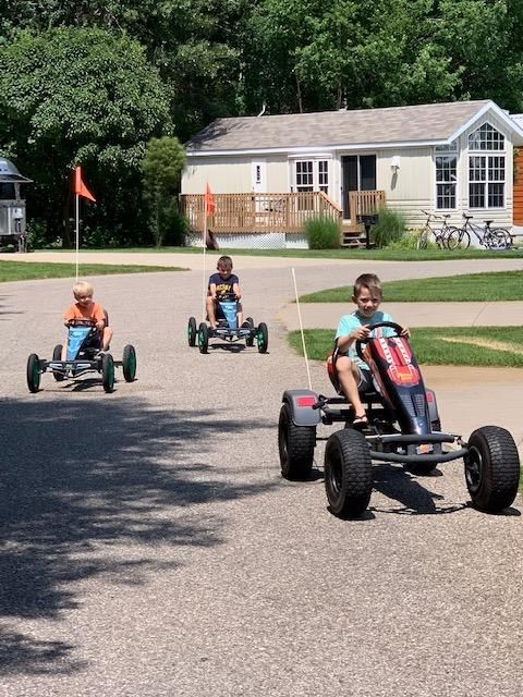 Three children are riding go karts down a street