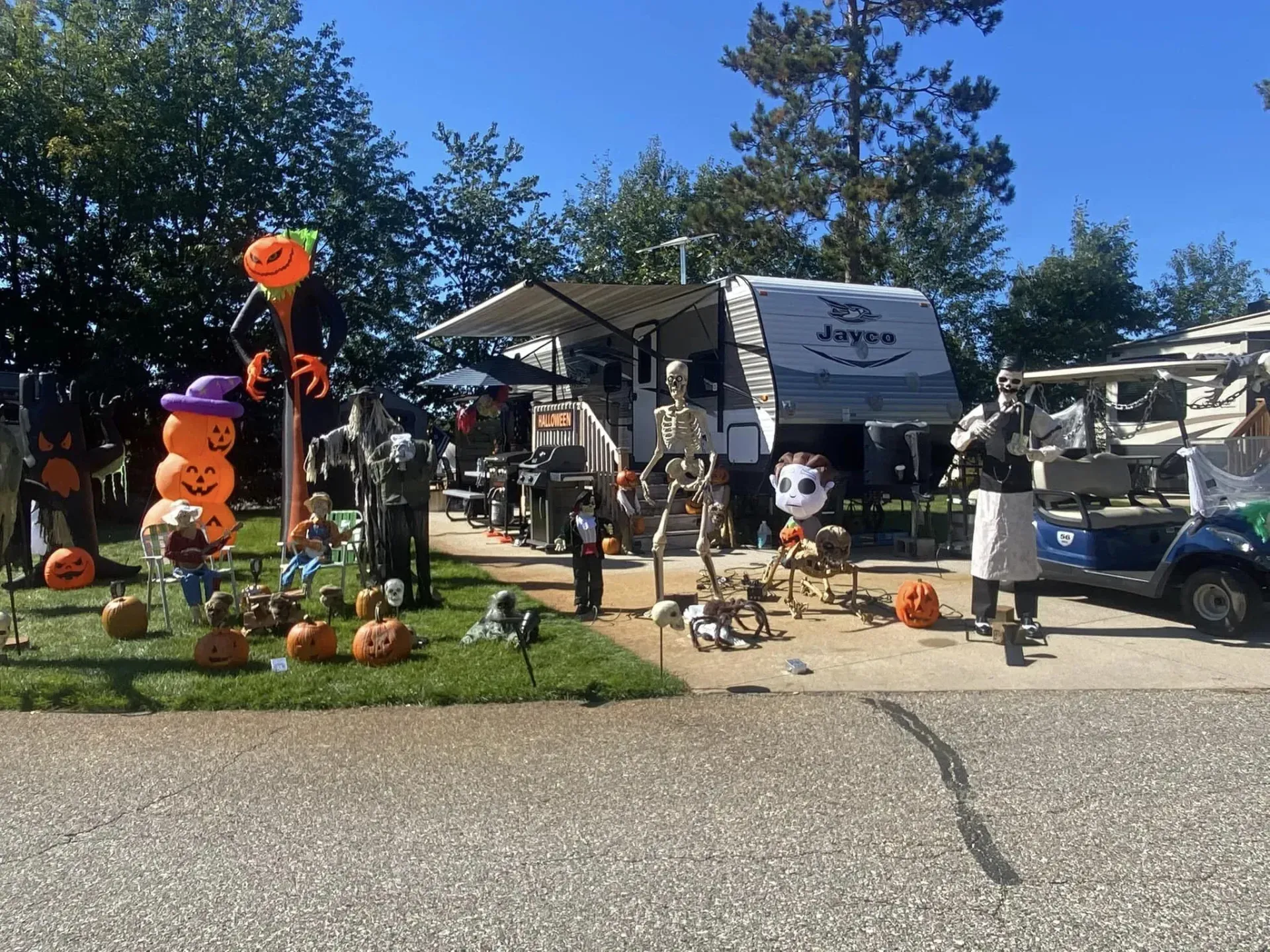 A rv is parked in front of a yard decorated for halloween.