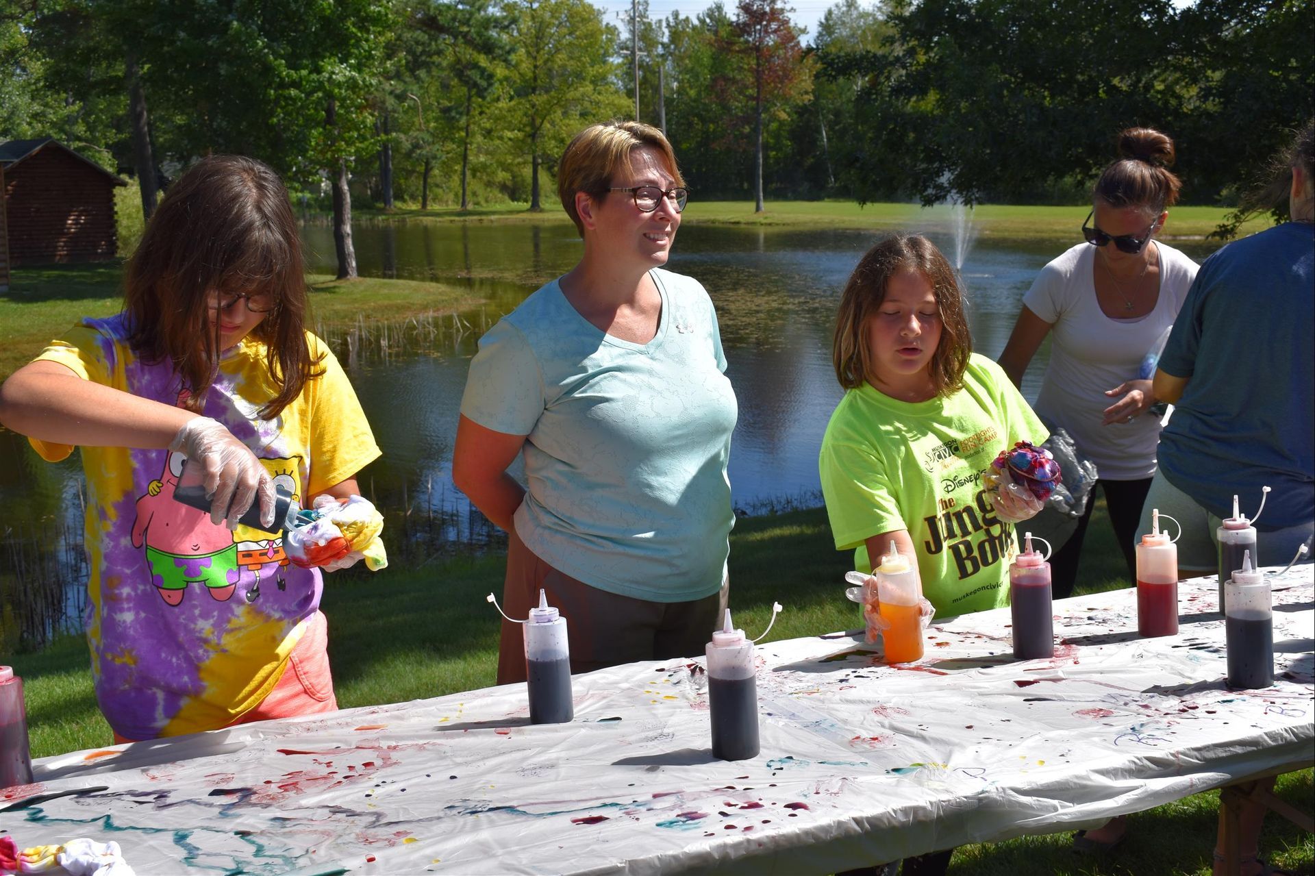 A group of people are standing around a table with bottles of paint on it.