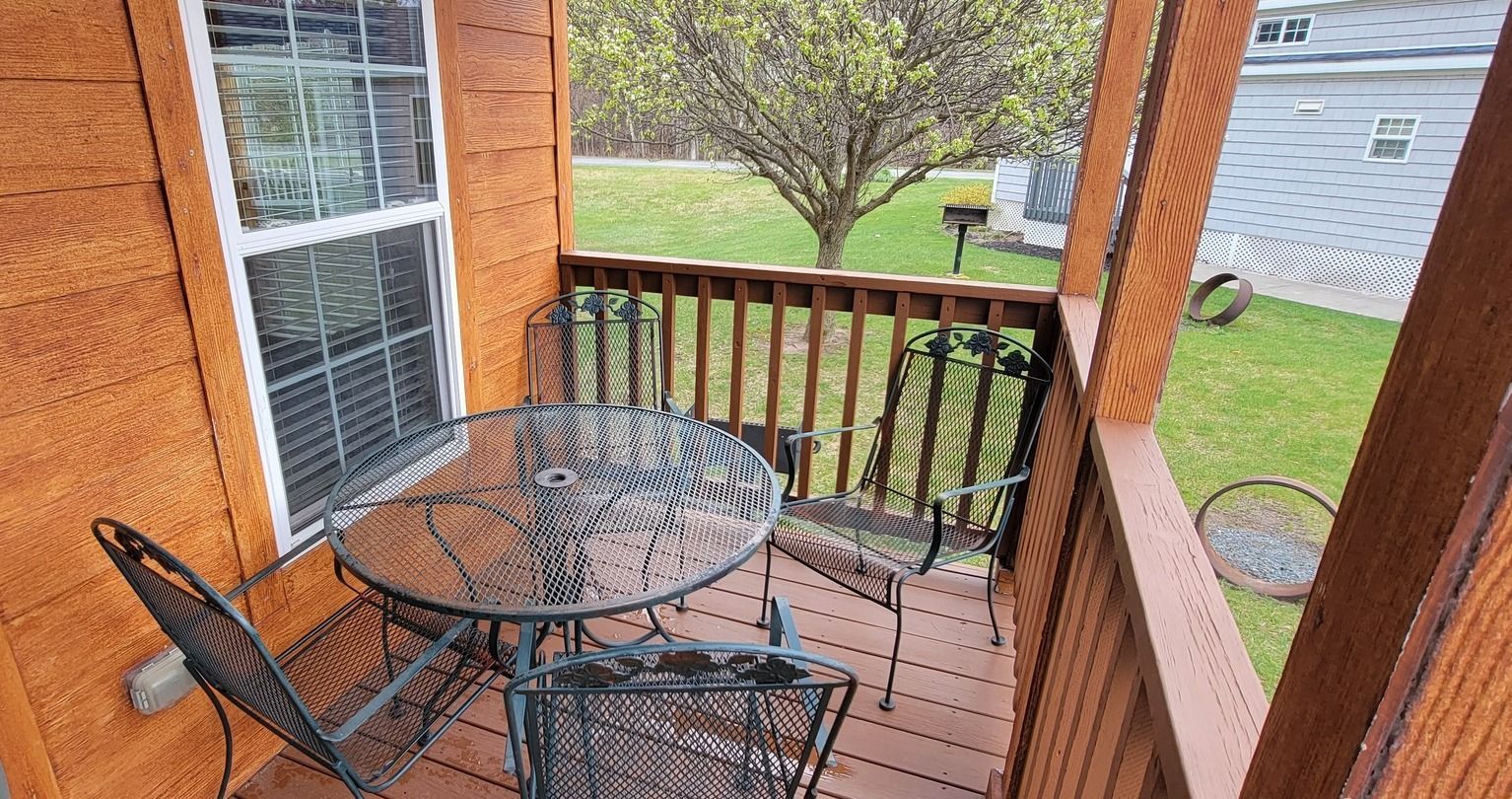 A small deck with a table and chairs on it.