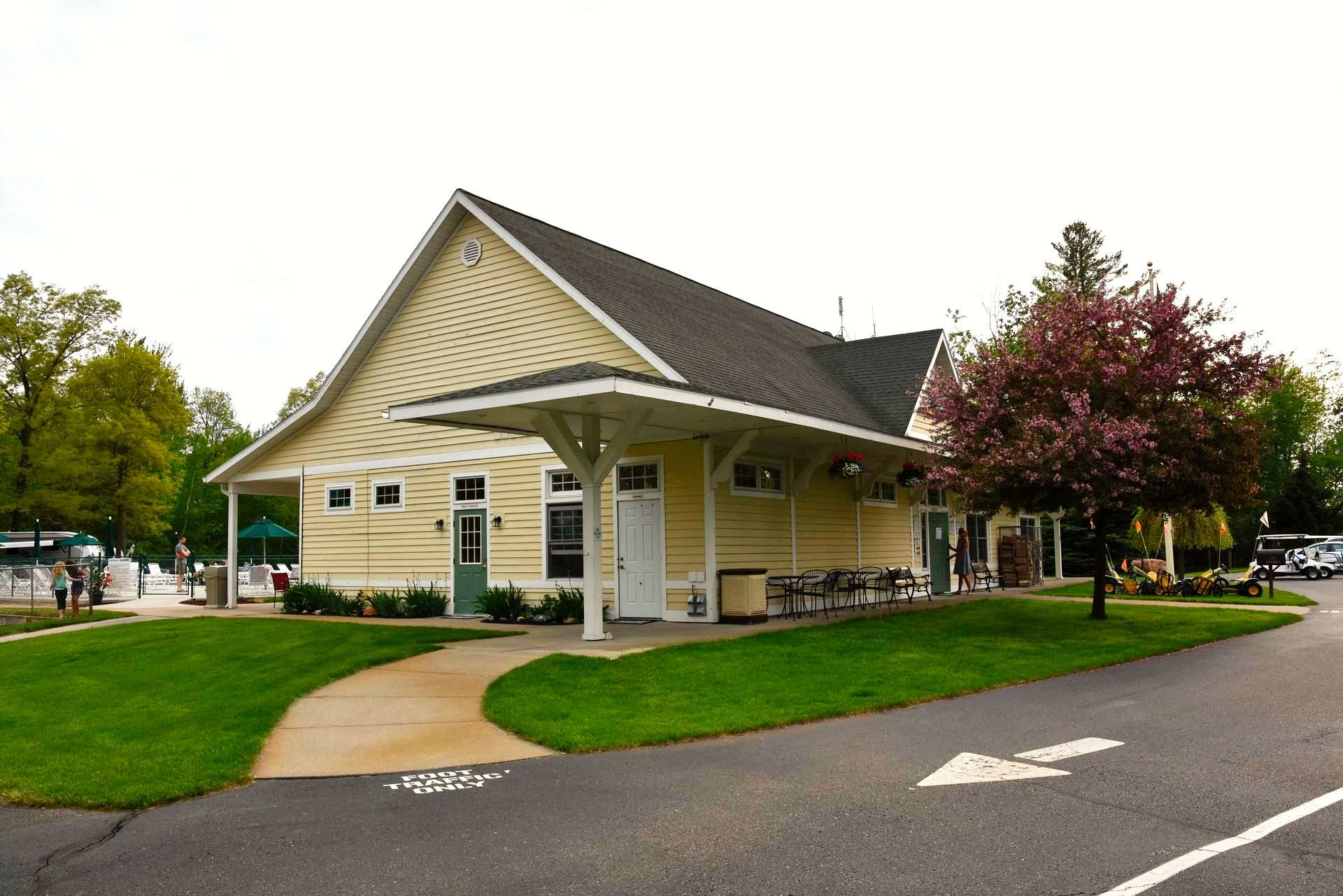 A yellow house with a gray roof and a tree in front of it