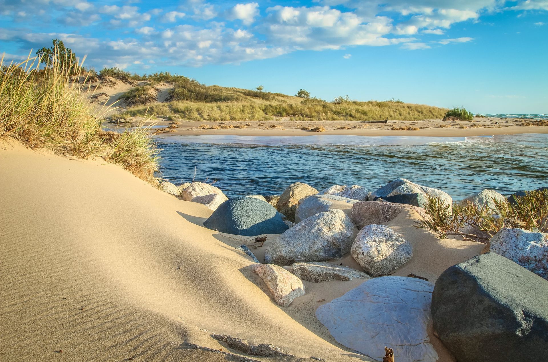 A sandy beach with rocks and a body of water in the background.