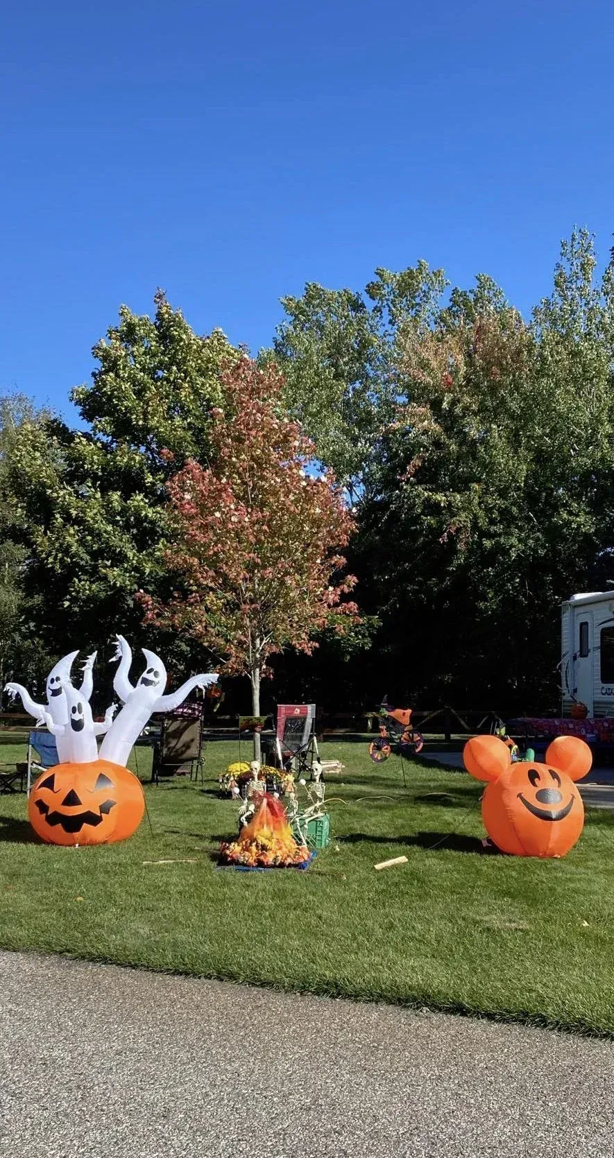 A couple of pumpkins and a ghost are sitting on top of a lush green field.