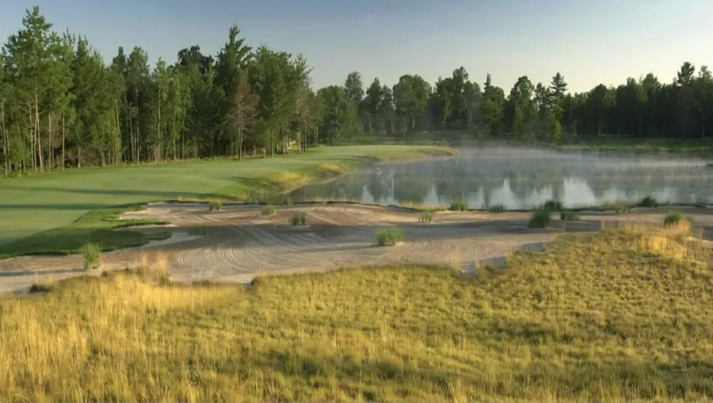 A golf course with a lake and trees in the background