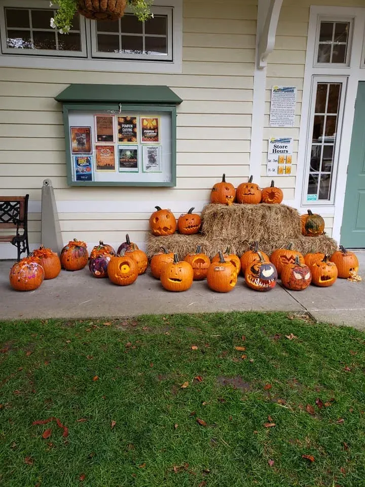 A bunch of pumpkins are sitting on the sidewalk in front of a house.
