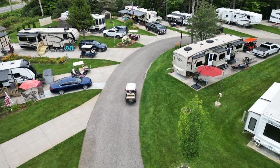A group of people are sitting at picnic tables in a park.