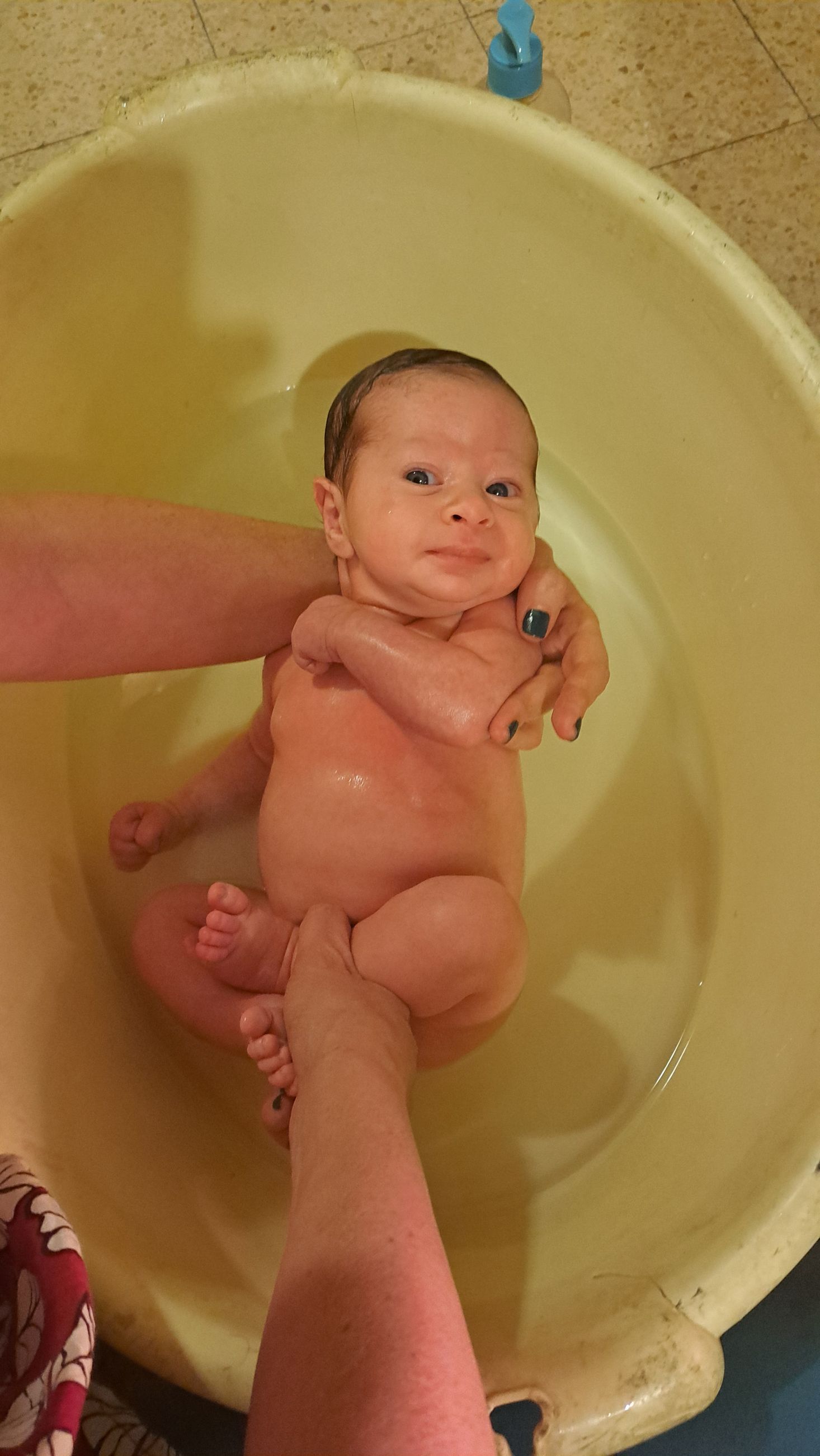 Baby in bath. Mother holds newborn in bath