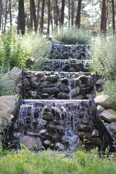 Stone tiered waterfall in a wooded setting. Water cascades down each level.