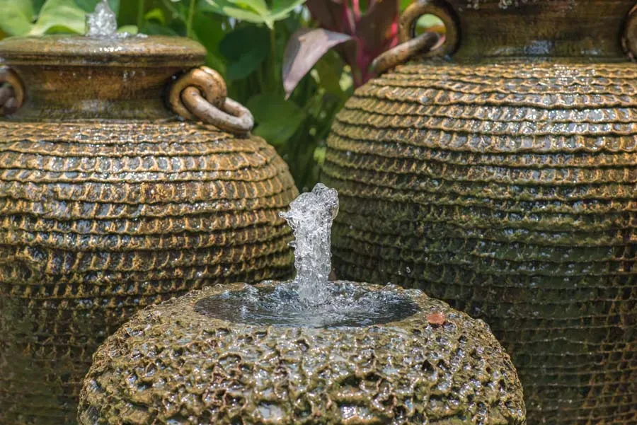 Water fountain feature with three textured brown pots, water spouts upwards.