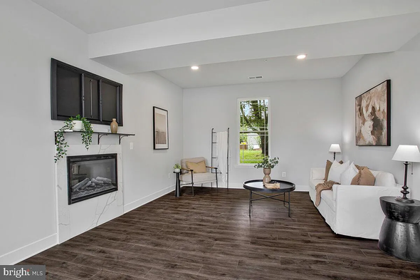 Living room with fireplace, white walls, dark wood floor, and white sofa.